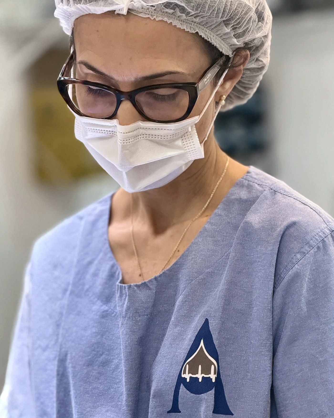 Dra. Vanessa Lima, de máscara e touca, no bloco cirúrgico durante um procedimento guiado por ultrassom